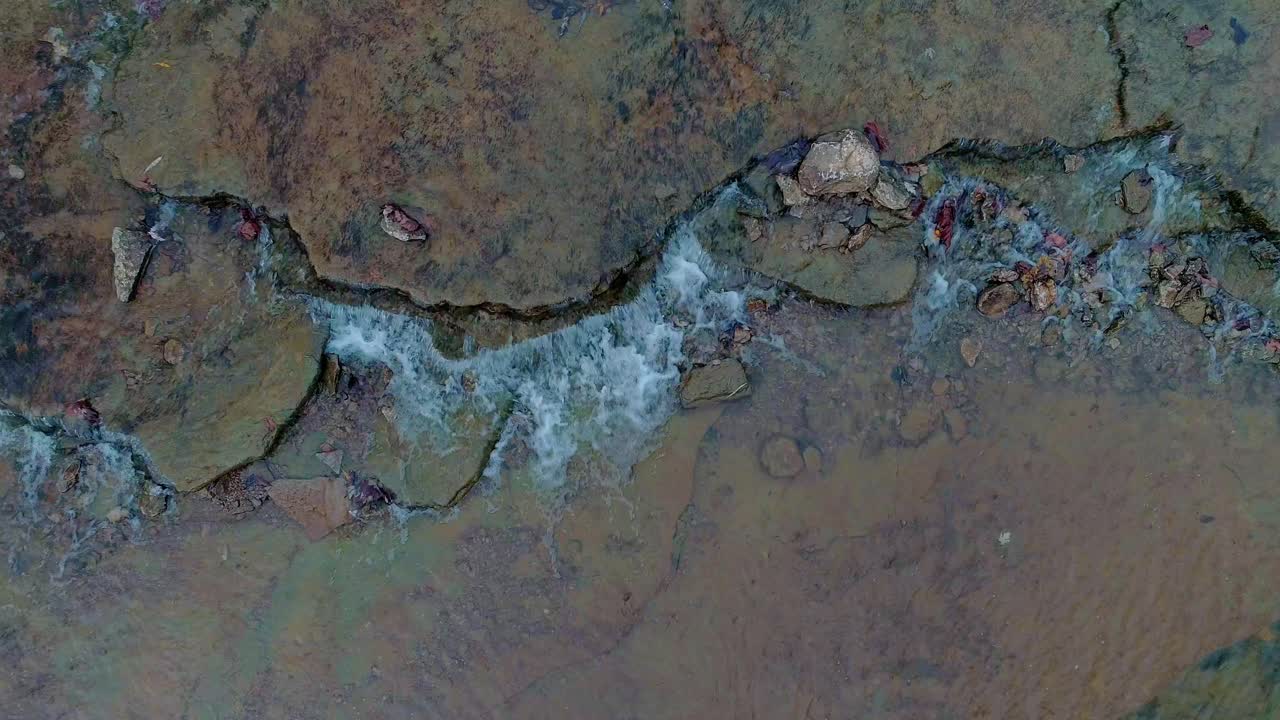 Gambar statis pemandangan meditatif, air mengalir di atas bebatuan warna-warni yang indah di Cedar Creek di Monterey, Kentucky.
