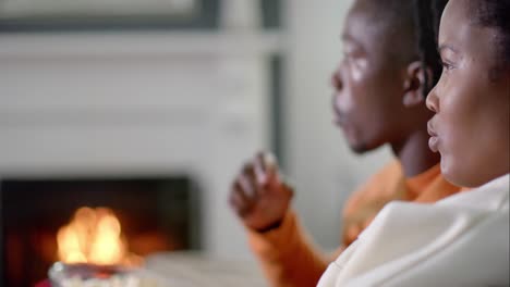 african american couple relaxing watching tv and eating popcorn at home, slow motion