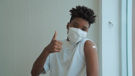 african american teenager showing covid-19 vaccine bandage merrily