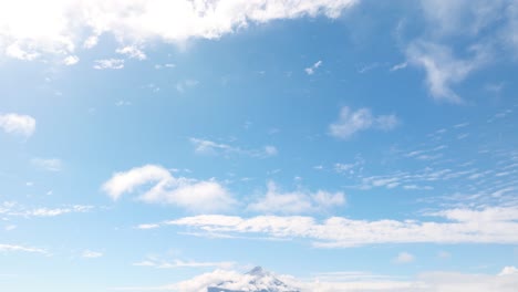 looking at at blue skies with clouds with pan down to reveal osorno volcano beside lake llanquihue in the distance