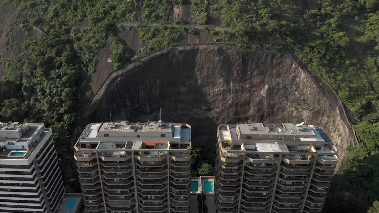 vista aérea de retroceso lento de condominios residenciales de gran altura que residen en la ladera de la montaña parcialmente cortada que revela toda la montaña detrás