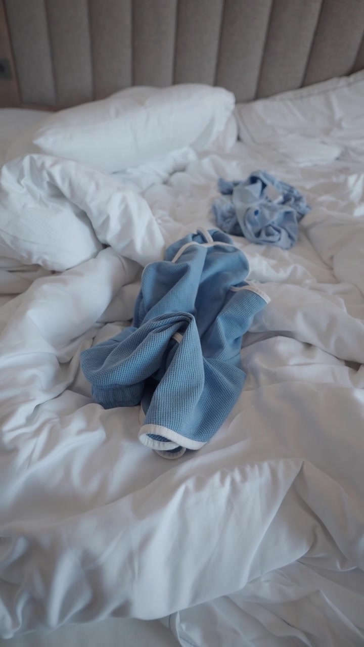 Letto sfatto con vestiti blu abbandonati