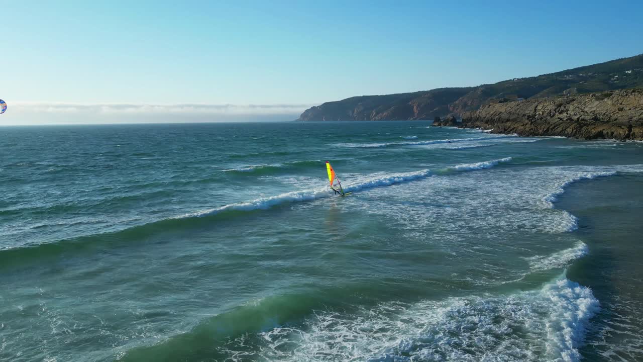 Flying along the sea following a windsurfer riding waves at guincho beach,Guincho beach It is very windy and offers excellent conditions for surfing, kitesurfing and windsurfing.Cascais,Portugal