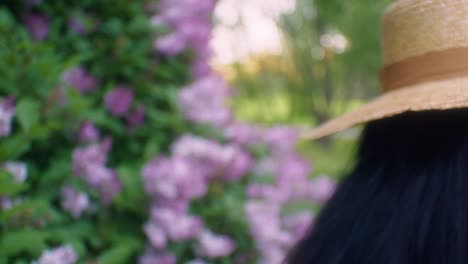 mujer negra caminando hacia flores lilas oliendo seguido