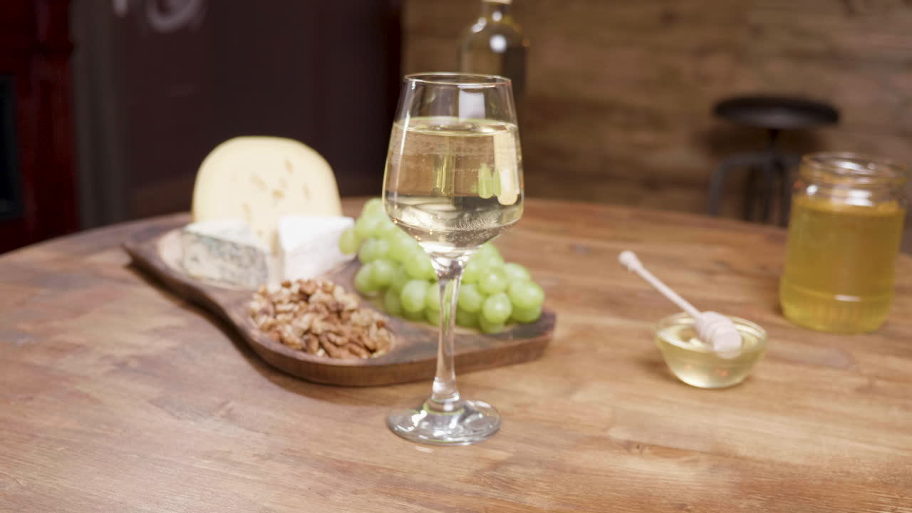 Wine, cheese, grapes, honey, and nuts on a wooden table