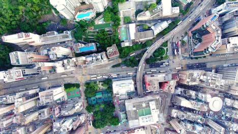 Traffic-passing-through-a-Car-park-building-in-downtown-Hong-Kong,-with-city-mega-buildings,-Aerial-view