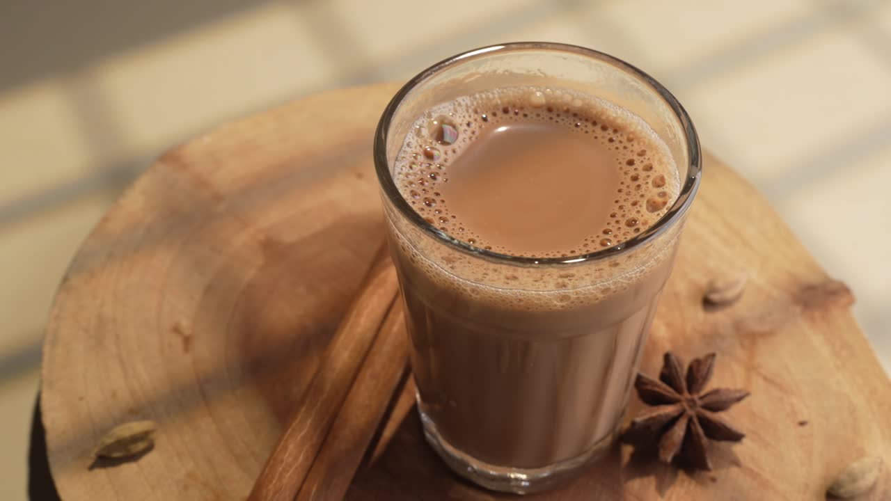 Chai indiano servito in tazze di vetro, preparato in una teiera di metallo con masala aromatici
