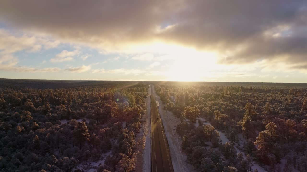 hermosa antena de amanecer mientras el auto pasa por debajo de la salida del sol de la carretera del bosque de invierno, 4k