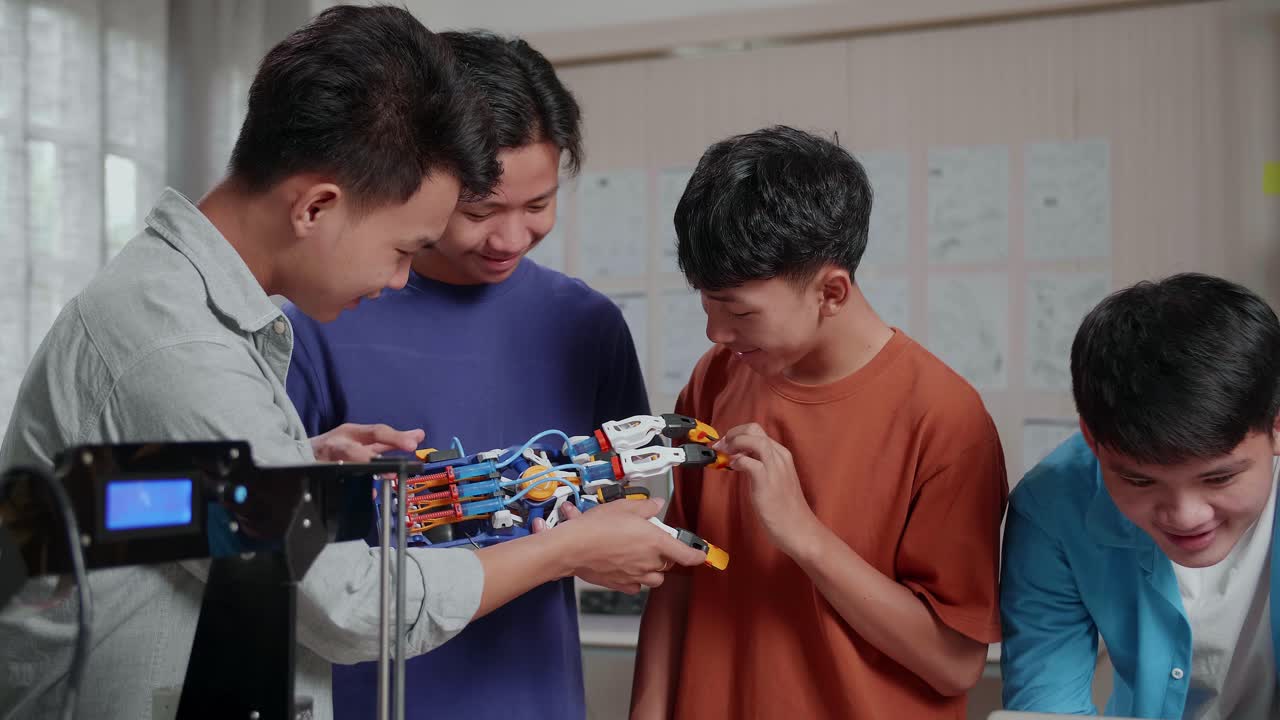 3d 프린팅을 사용한 젊은 아시아 소년 그룹이 집에서 일하는 동안 노트북의 사진과 사이보그 손을 비교합니다.