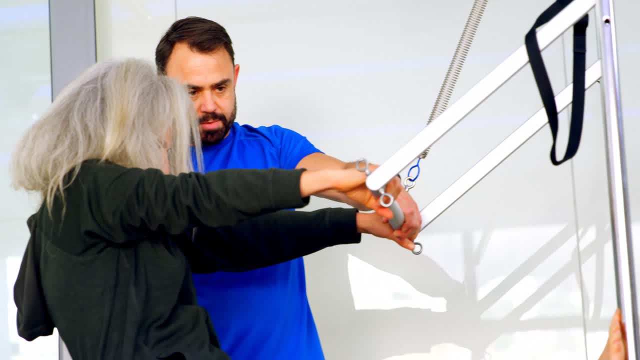 entrenador ayudando a una mujer mayor en la realización de yoga 4k