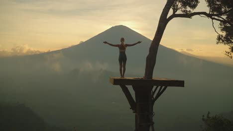 frau streckt und streckt die arme aus, während sie bei sonnenuntergang auf den berg agung blickt, lahangan süß