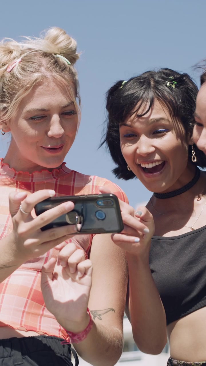 Three Young Women Laughing and Taking a Selfie Outdoors