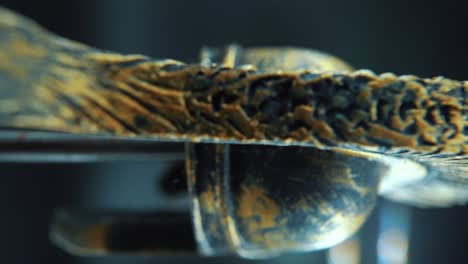 una toma cinematográfica macro vertical de un diseño de rostro espartano, casco de bronce de metal guerrero, en un soporte giratorio, iluminación de estudio, movimiento lento de 4k