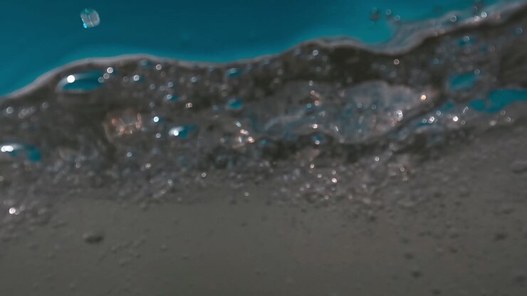 Half underwater first person view of sea waves splashing on camera