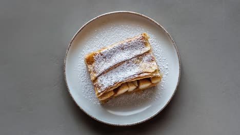 Delicious-Apple-Strudel-Pastry-on-White-Plate-with-Powdered-Sugar