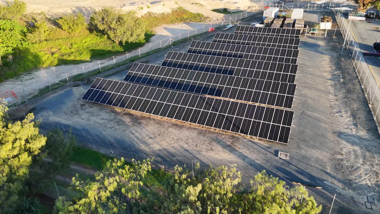 Aerial footage of solar panels on sandy terrain, captured in bright daylight with a drone, showcasing renewable energy infrastructure