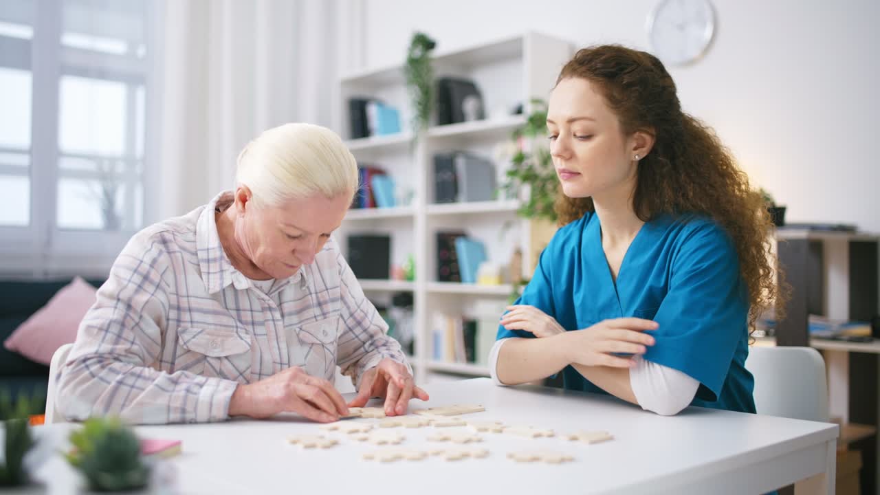 간호사가 시니어 여자를 지켜보고 퍼즐을 연결하고, 뇌를 위한 운동