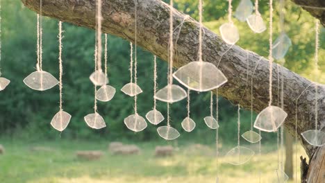 creative installation of pieces of glass hanging on a tree against a sunset background, glitters beautifully