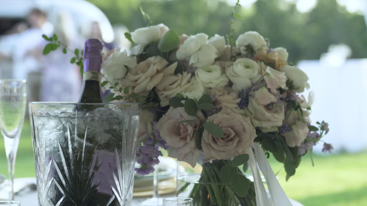 Bouquet di fiori accompagnato da una bottiglia di champagne al tavolo nuziale.