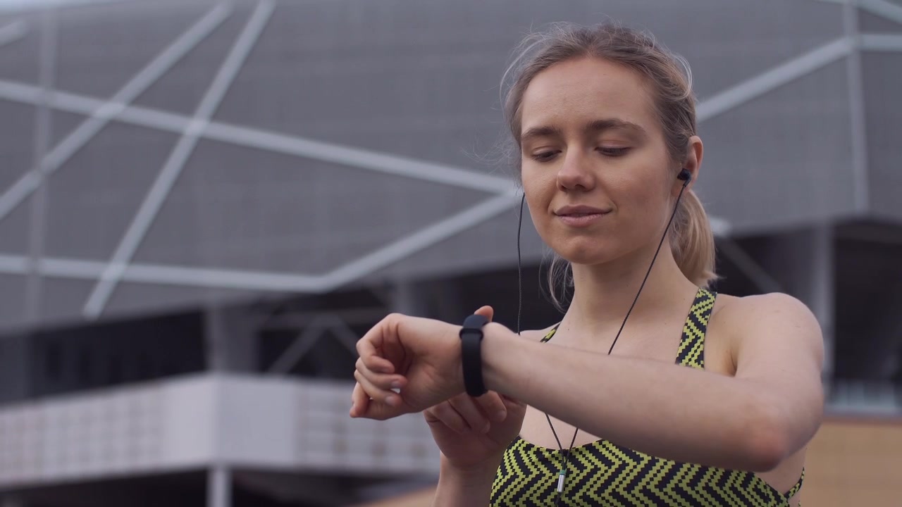 Giovane Donna in Abbigliamento Sportivo Controlla lo Smartwatch All'aperto