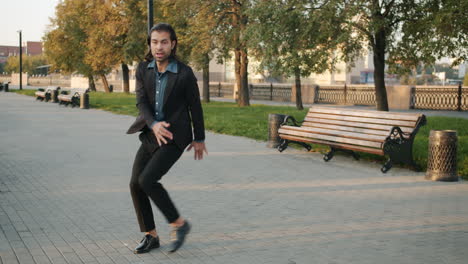 man in a black suit walking in a park