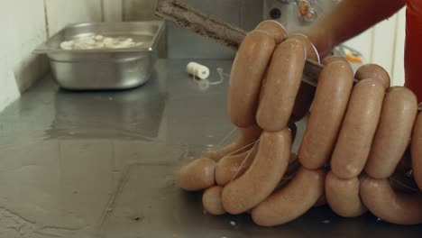 hanging raw sausage on bars for smokehouse