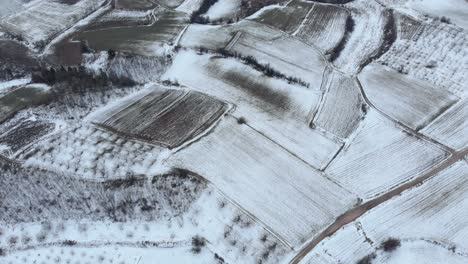 Vista-Aérea-De-Pájaro-De-Los-Campos-Agrícolas-Nevados-De-Montaña-En-Invierno-Día-Inclinado