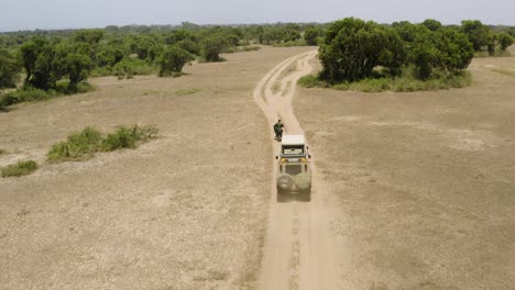 Safari-jeeps-and-motorcycle-drive-through-Africa-plains-in-the-burning-midday-sun