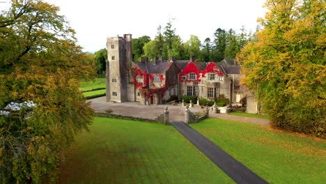 drone slow approach castle through symmetrical tree lined path with vibrant orange fall tones