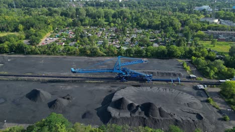 spreader reclaiming coal excavator at a coal terminal near residential area. amazing aerial view flight overflight flyover drone