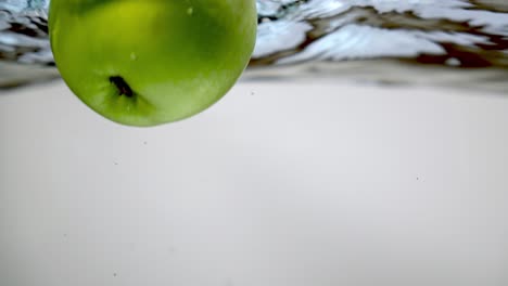 dos manzanas verdes frescas cayeron en un tazón de agua, tiro bajo el agua