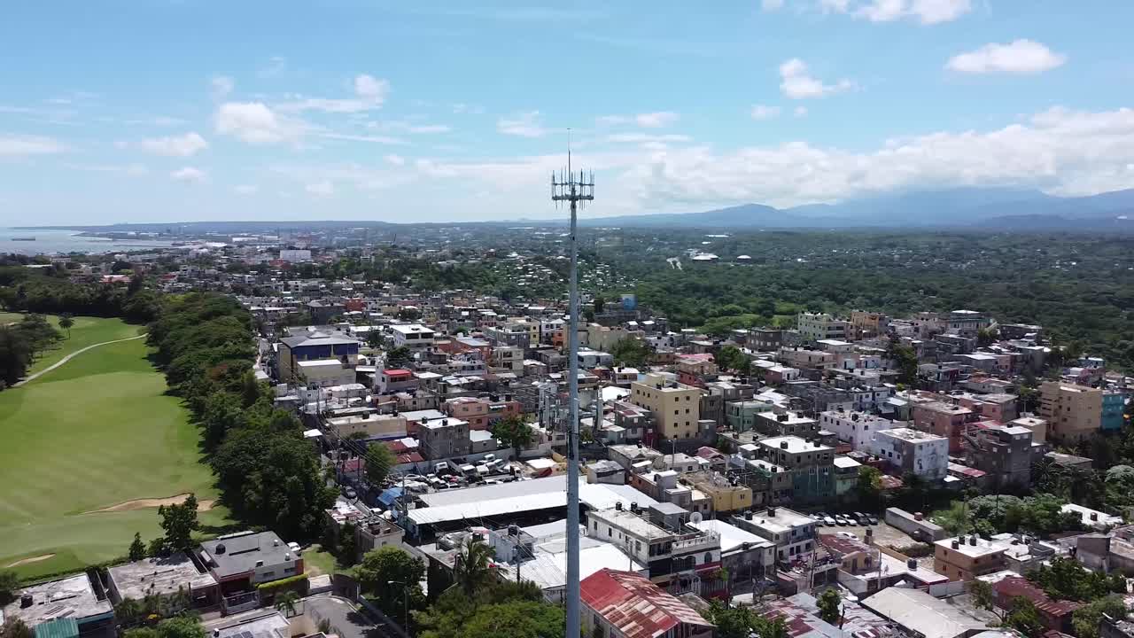 vista aérea de aviones no tripulados de casas residenciales que muestra una antena de comunicaciones en panorámica con el fondo de la zona residencial y el área de tugurios, video uhd en un hermoso cielo azul
