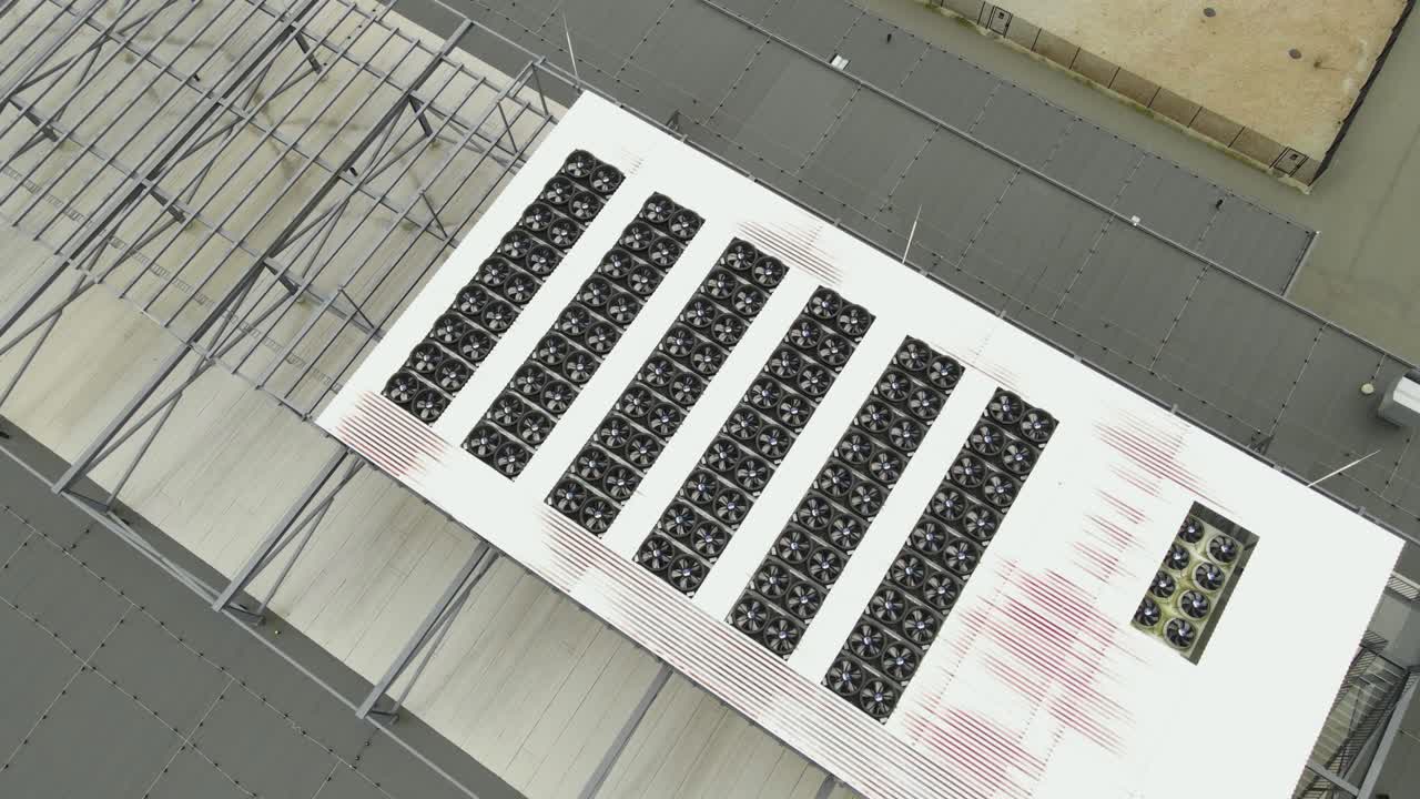 Aerial drone video of AI data center cooling system fans spinning on a modern technology building during a sunny day. The system is keeping data and chips cool in the building by spinning fast