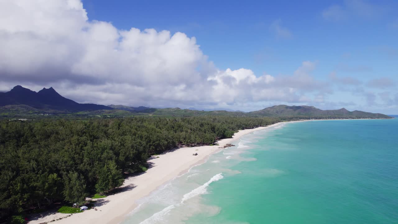 imágenes de drones que descienden desde montañas púrpuras profundas y vegetación exuberante hasta playas de arena blanca y aguas turquesas de la bahía de waimanalo, oahu, el paraíso de hawai.