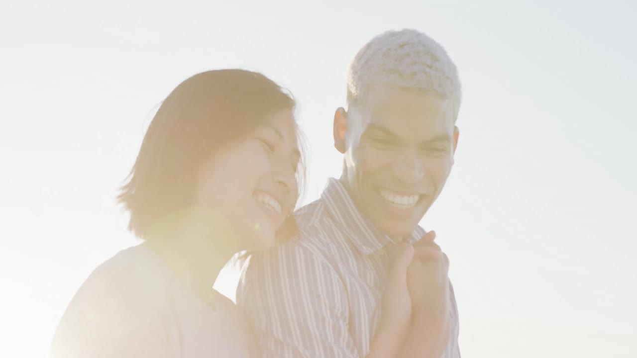 슬로우 모션으로 해변에서 손을 잡고  ⁇ 고 있는 행복한 두 인종 커플