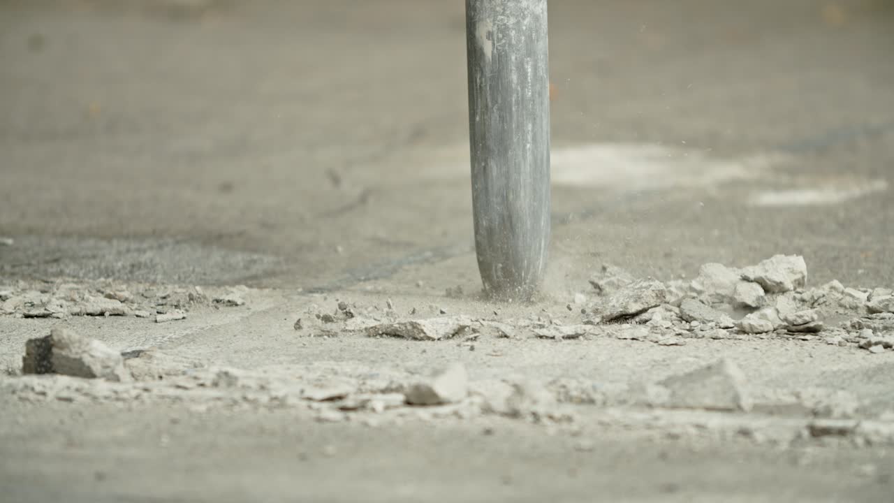 Close-up of excavator hydraulic arm rock breaker working on concrete road.Slow Motion