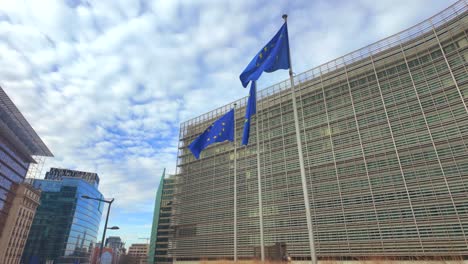 view of european union flags fluttering beside modern glass architecture