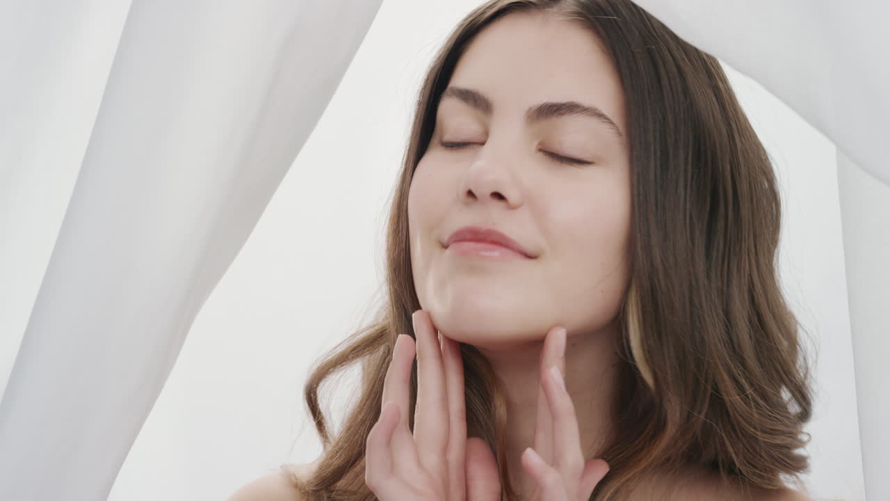 초상화 아름다운 젊은 여성이 사정을 마사지하고 부드러운 건강한 피부를 만지고 손으로 얼굴을 만지고 부드러운 자연 피부를 즐기고  ⁇ 색 배경의 여성적인 아름다움