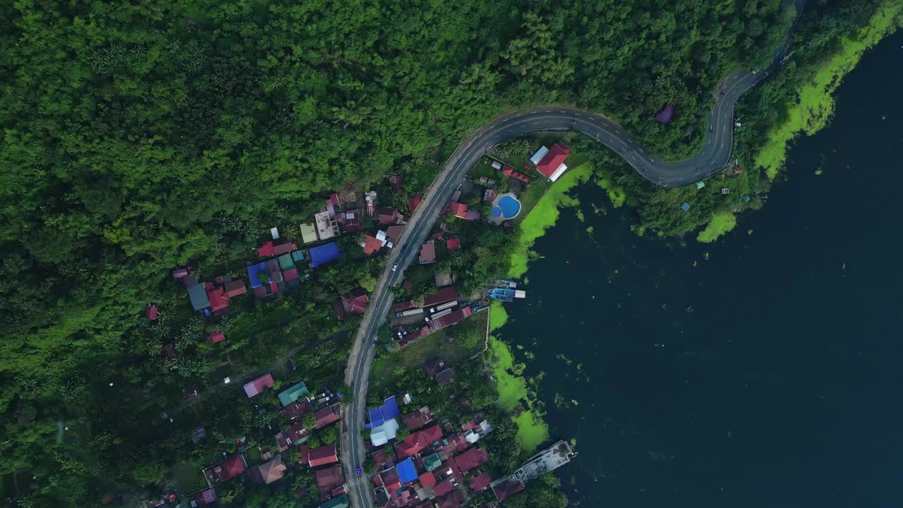 A top-view aerial of winding road and hillside homes along the forested edge of Taal Lake in Talisay, Batangas, Philippines