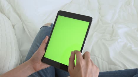 mujer sosteniendo una tableta digital con pantalla verde y dispositivo táctil navegando por internet.
