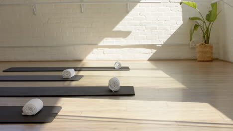 sunlight streams through the window, lighting up rolled yoga mats on wood floor