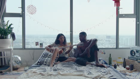 man enjoying the song of girlfriend playing the guitar in bedroom