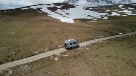 aerial panning of camper van driving through snowy plateau, montenegro