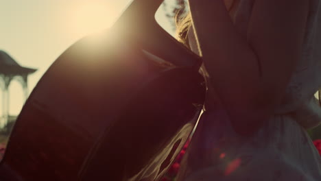 sun reflection on cello outdoors. unknown girl playing cello in park daytime.