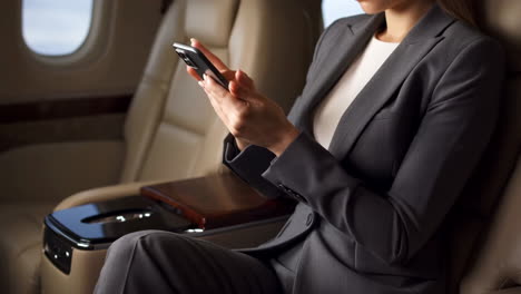 businesswoman using a smartphone in a private jet