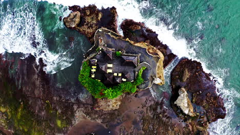 top shot of tanah lot hindu temple on sea rock washed by waves, bali