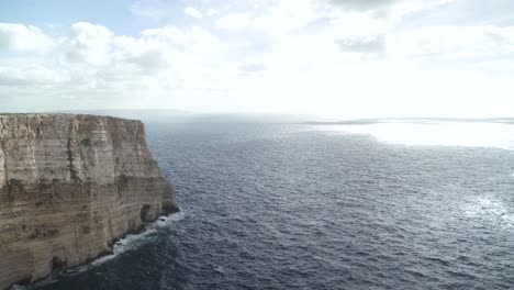 Langsamer-Panoramablick-Auf-Die-Felsen-Von-Ta-Cenc-Und-Das-Blaue-Mittelmeer-Mit-Heller-Sonne,-Die-Am-Wintertag-Scheint