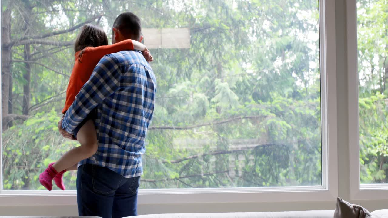아버지 는 집 에서 창문 근처 에 서 있을 때 딸 을 들고 있다 4k