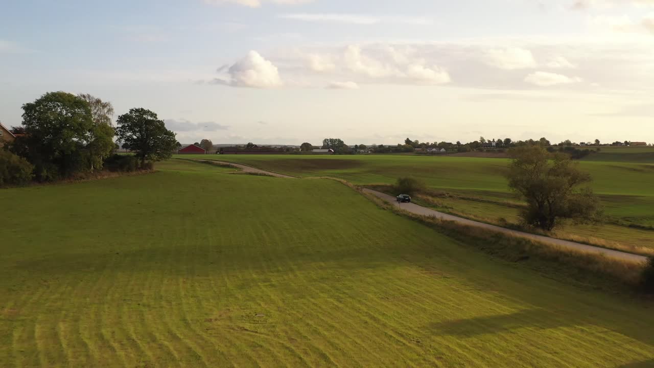 스웨덴 남부의 들판을 달리는 자동차, 고속으로 비행하는 4k 드론으로 포착