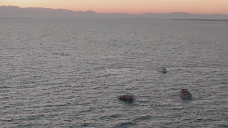 Glowing-sunset-horizon-over-group-of-small-boats-sailing-together-on-the-Mediterranean-sea